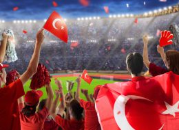 Turkey football supporter on stadium. Turkish fans on soccer pitch watching team play. Group of supporters with Türkiye flag and national jersey cheering for Turkiye. Championship game.